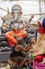 An artisan gives final touches to an idol of the elephant-headed Hindu deity Ganesha at a workshop