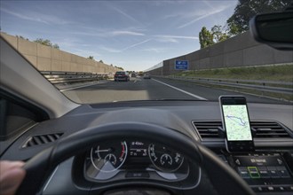 Driving on the A73 motorway with navigation by mobile phone, noise barriers on the left and right,