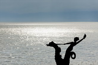 Sculpture with mermaid against the light on the promenade in Vevey on Lake Geneva, Vaud,