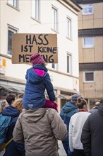 Child carried on shoulders, holding protest sign at demonstration, Against right-wing