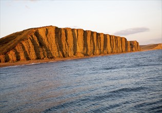 Golden afternoon light on sandstone cliffs, East Cliffs, West Bay, Bridport, Dorset, England, UK