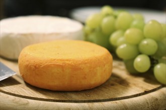 Cheese platter with various types of soft cheese and grapes