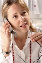 A blonde woman telephoning with Pocket PC, mobile phone, telephone, studio