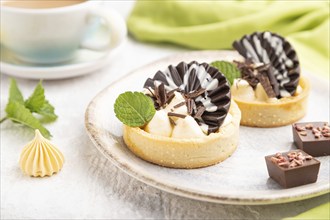 Sweet tartlets with chocolate and cheese cream with cup of coffee on a gray concrete background and