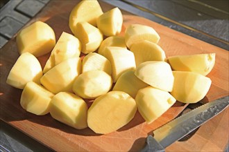 Peeled cut chopped potatoes on chopping board with kitchen knife