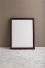 Brown wooden frame mockup on beige paper background. Blank, vertical orientation, still life, copy