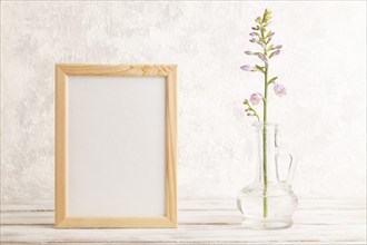 Wooden frame with hosta flowers in glass vase on gray concrete background. side view, copy space,