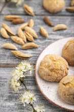 Almond cookies and a cup of coffee on a gray wooden background and green linen textile. Side view,