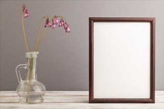 Wooden frame with pink dicentra, broken heart in glass on gray pastel background. side view, copy