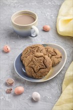 Homemade oatmeal cookies with a cup of cocoa and a yellow textile on a gray concrete background.