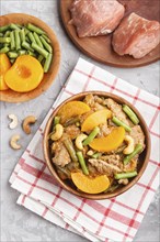 Fried pork with peaches, cashew and green beans on a black concrete background. top view, close up,