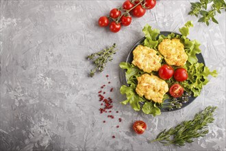 Minced chicken cutlets with lettuce, tomatoes and herbs on a gray concrete background. top view,