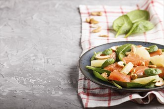 Fresh salmon with pineapple, spinach and cashew on a gray concrete background. Side view, copy