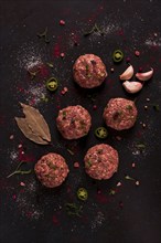 Raw meatballs, with micro greenery, with spices, on a black background, top view, homemade, no