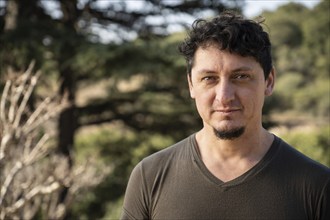 Close-up portrait of middle-aged caucasian man with a gaze and slight smile outdoors