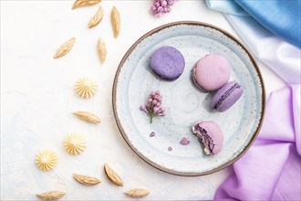 Purple macarons or macaroons cakes with cup of coffee on a white concrete background and