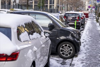 Winter in the city, small Smart car has used a tiny parking space to park sideways, in the city