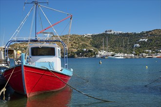 Fishing boat in a quiet harbour, surrounded by blue sea, coast and a clear sky, Skala, Patmos,