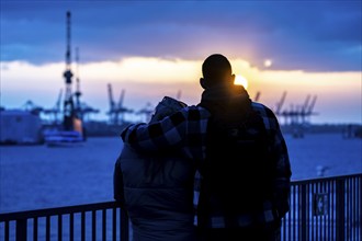 Port of Hamburg, couple looking at the Blohm + Voss shipyard, evening, cranes of the container