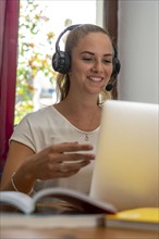 Young student learns at home, online, in conversation with other students