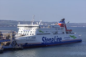 Large ferry with colourful design docked in harbour surrounded by calm waters, Belfast