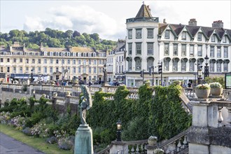 Historic buildings with ivy in front of a cityscape in sunny weather, Bath