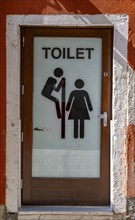 Entrance door to a public toilet, funny, pictogram with man looking over a partition wall at a