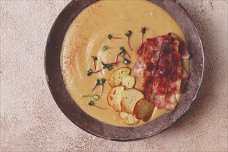 Pumpkin cream soup, curry, fried bacon, bruschetta chips, micro-greens, top view, no people