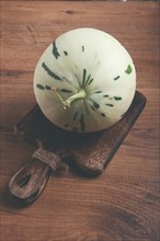 Dino melon, white with green stripes, small size, on the table, close-up, no people