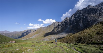 Mountaineers on a hiking trail, green high valley, Keldike Valley on the way to the Ala Kul Pass,