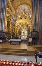 Baroque church interior with golden decorations, altar and burning candles in the foreground,