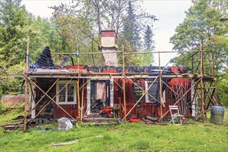 Red idyllic old wooden cottage that has burned down in the forest, Sweden, Europe