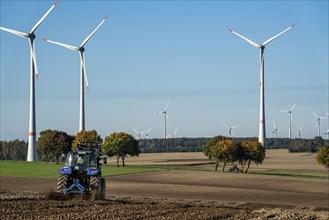 Farmer working in the fields, with a tractor, wind farm above the village of Lichtenau,