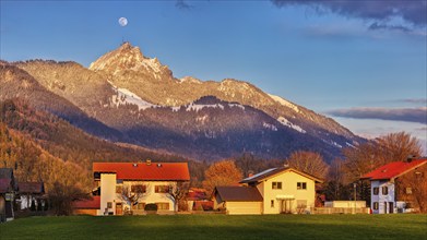 Sunset over an alpine scene with houses in the foreground, snow-covered mountain in the background