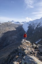 Mountaineer standing on a rock, surrounded by an impressive mountain landscape with snow-covered