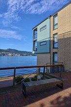 Modern residential building on the waterfront with mountain views under a blue sky with scattered