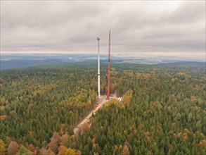 An almost finished wind turbine in autumn forest with a wide view, wind farm construction site,