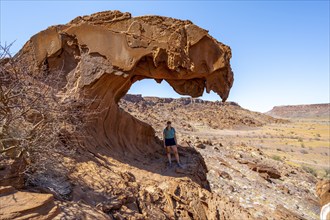 Young woman standing in a rock formation Lion's Mouth, Twyfelfontein, desert landscape, Kunene,