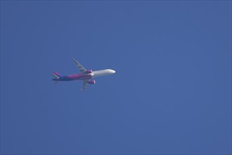 Airbus aircraft of Wizz air airlines flying across a blue sky, England, United Kingdom, Europe