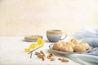 Almond cookies and a cup of coffee on a white concrete background and blue linen textile. Side