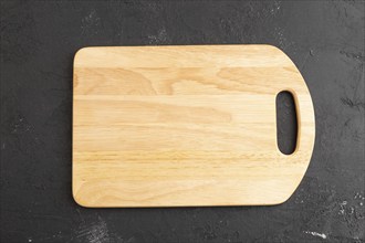 Empty rectangular wooden cutting board on black concrete background. Top view, close up, flat lay