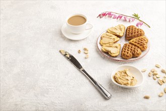 Homemade waffle with peanut butter and cup of coffee on a gray concrete background. side view, copy