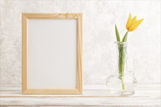 Wooden frame with orange tulip flower in glass on gray concrete background. side view, copy space,