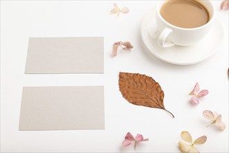 Composition with gray paper business card, brown beech autumn leaves, hydrangea flowers and cup of