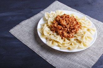 Farfalle bolognese pasta with minced meat on black wooden background. close up, copy space