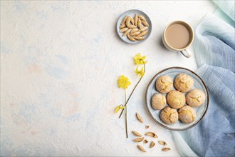 Almond cookies and a cup of coffee on a white concrete background and blue linen textile. Top view,