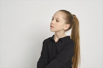 Portrait of nine years girl with smooth face skin and long ponytail in profile on white background