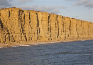 Golden afternoon light on sandstone cliffs, East Cliffs, West Bay, Bridport, Dorset, England, UK