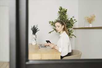 View through the window of a woman working in bright office