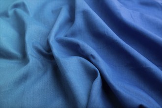 Fragment of cotton blue tissue. Side view, natural textile background and texture. wave concept,